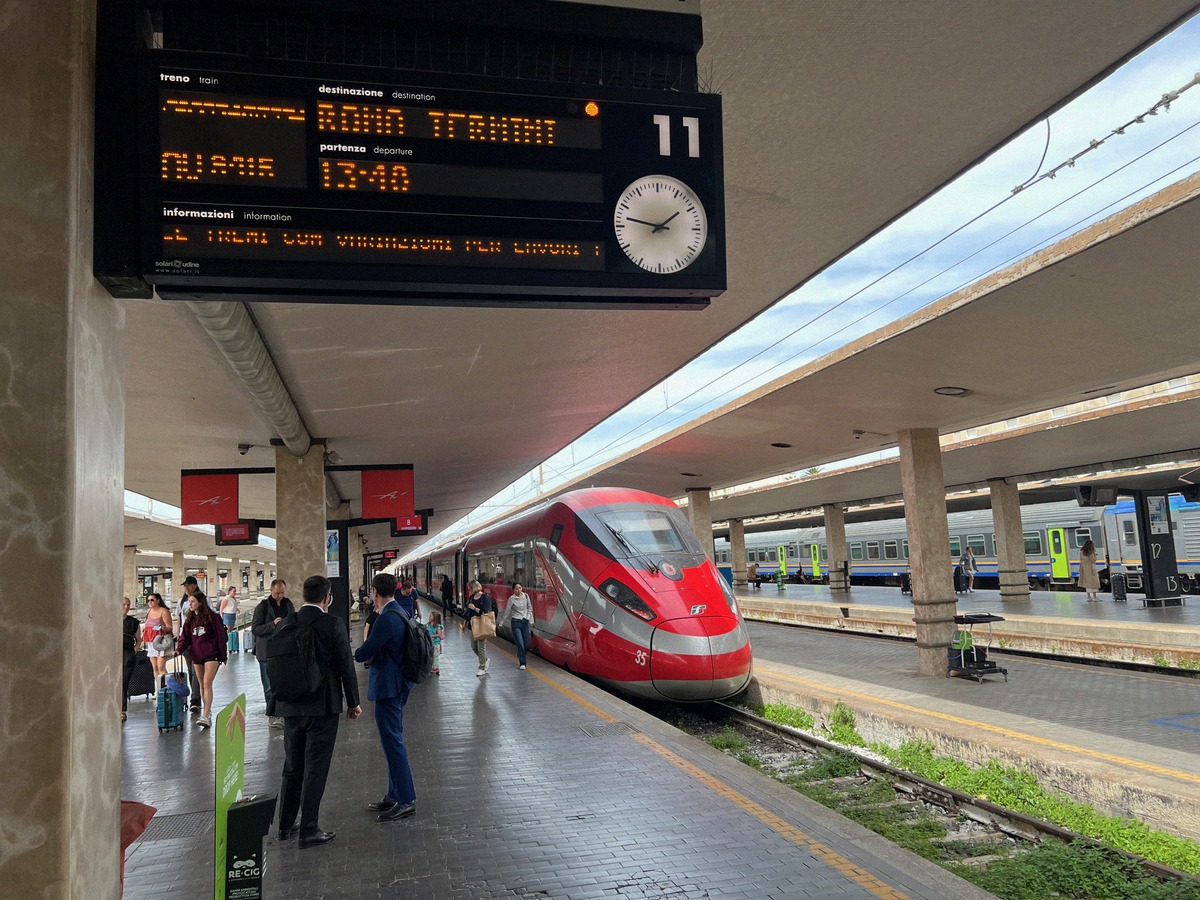 A red Frecciarossa high-speed train at platform 11 of Florence Santa Maria Novella station.