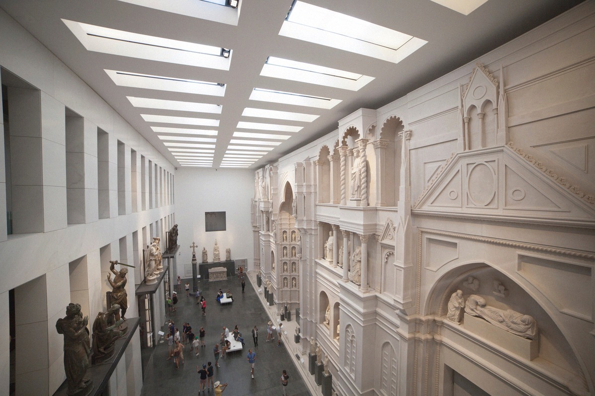 A light-filled hall of the Opera del Duomo Museum with the reconstruction of the medieval cathedral facade.