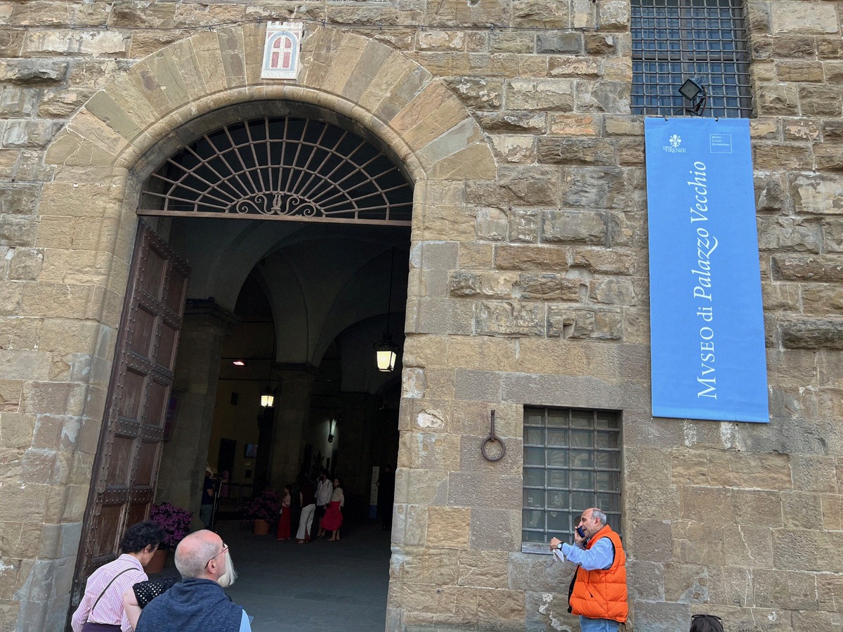 The stone entrance of the Palazzo Vecchio with the sign of the museum and the Florentine lily.